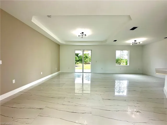 Empty room featuring a tray ceiling and light marble finish floors