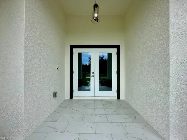 Property entrance with french doors, a patio area, and stucco siding