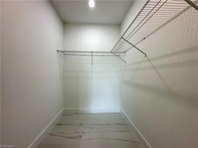 Walk in closet featuring light marble finish flooring