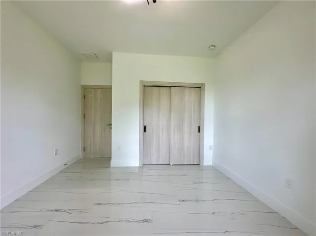 Unfurnished bedroom featuring light marble finish flooring and a closet