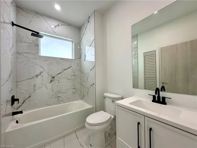 Bathroom featuring vanity and a combined bath / shower with marble appearance