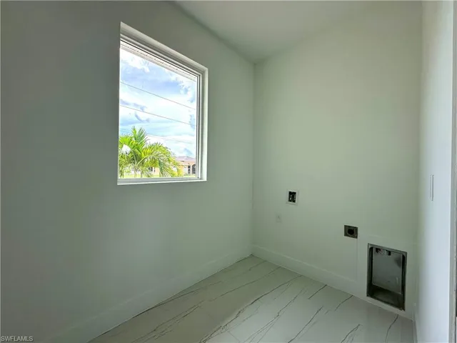 Laundry room with hookup for an electric dryer, light marble finish floors, and hookup for a washing machine