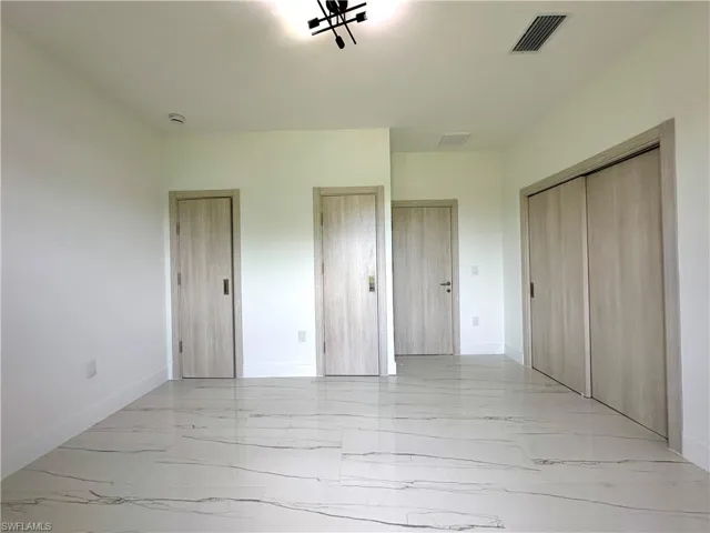 Unfurnished bedroom featuring light marble finish flooring