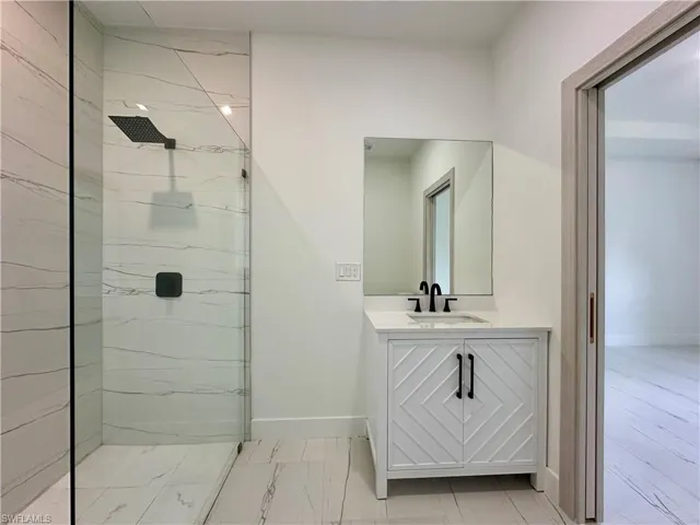 Bathroom with vanity and a marble finish shower