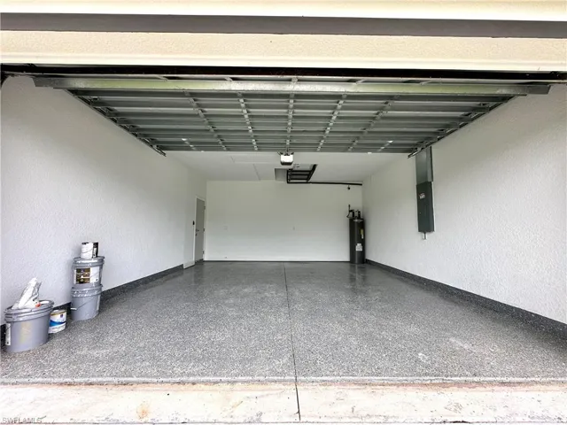 Garage featuring a textured wall, electric panel, and electric water heater