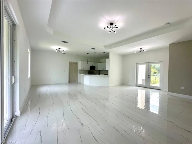 Unfurnished living room with french doors and a tray ceiling