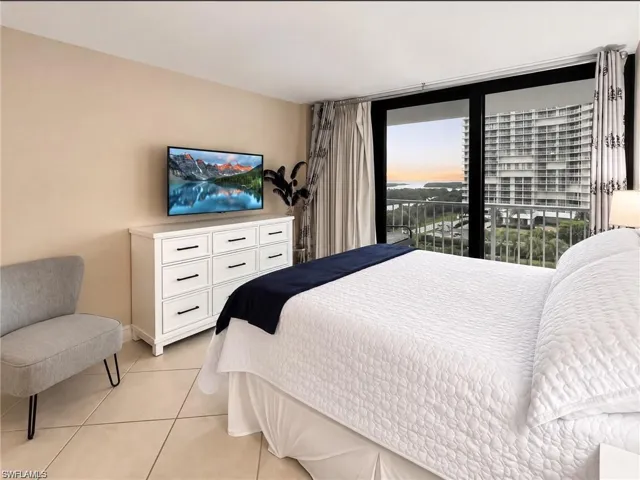 Large format tile flooring, black-framed sliding glass doors, and a private balcony with water and coastal landscape scenery