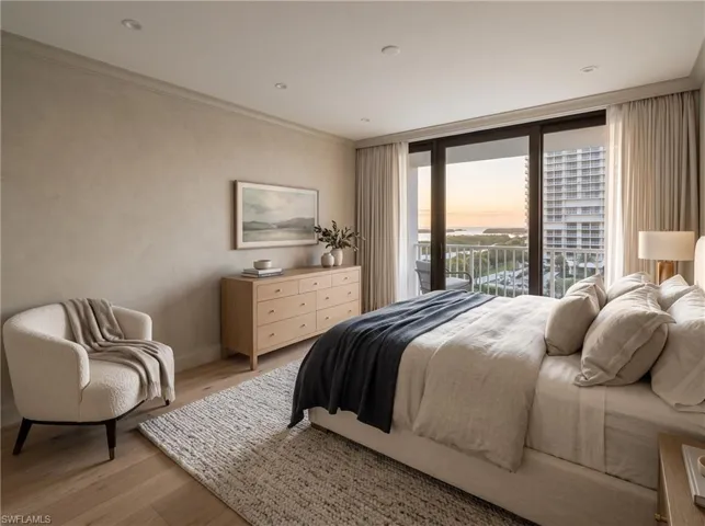 Floor-to-ceiling glass sliding doors opening to a private balcony, light-toned wood-finish flooring, recessed lighting, and neutral-toned wall finish. virtually staged