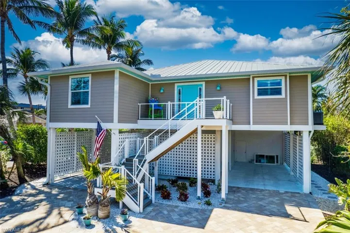View of front of home featuring a carport, a patio, stairs, and a wooden deck