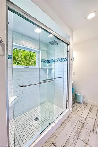 Bathroom featuring a stall shower, recessed lighting, and wood finish floors