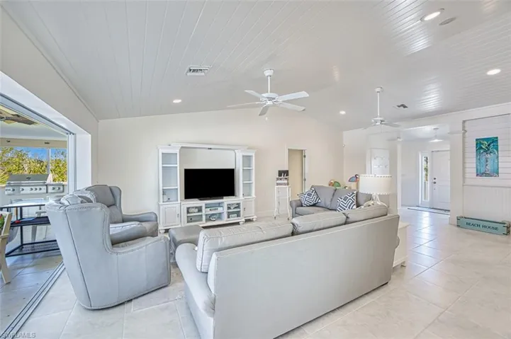 Living room with a ceiling fan, lofted ceiling, plenty of natural light, wood ceiling, and light tile patterned flooring