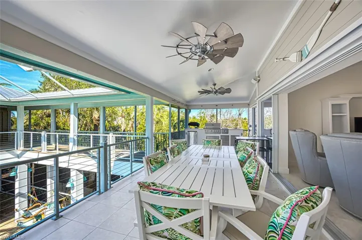 Sunroom featuring an outdoor kitchen, ceiling fan, vaulted ceiling, and outdoor dining area