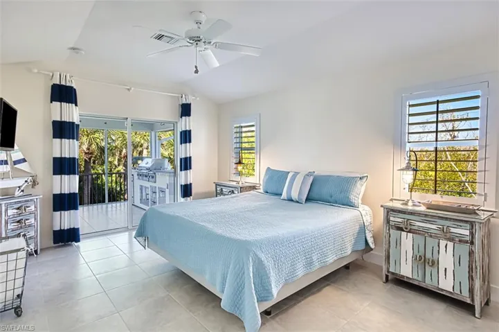 Bedroom featuring vaulted ceiling, access to outside, ceiling fan, multiple windows, and light tile patterned floors