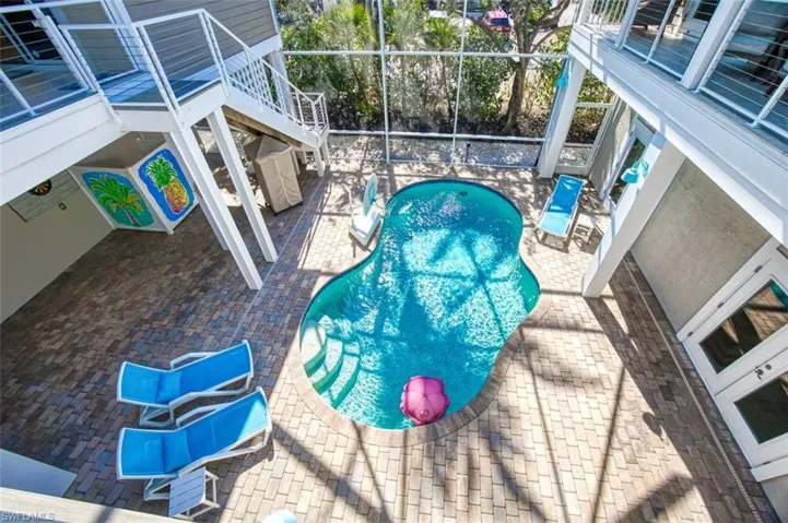 Outdoor pool with a patio, glass enclosure, and stairway