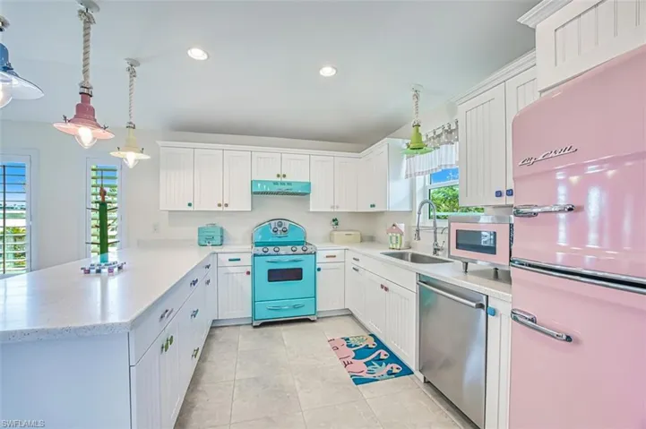 Kitchen with freestanding refrigerator, hanging light fixtures, white cabinetry, a peninsula, and recessed lighting