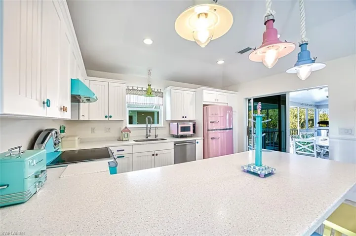 Kitchen featuring white cabinetry, a peninsula, appliances with stainless steel finishes, hanging light fixtures, and recessed lighting