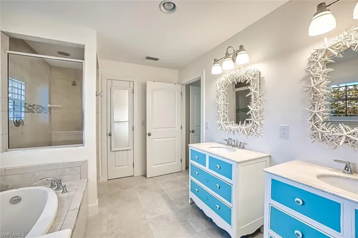 Bathroom with two vanities, a garden tub, a shower stall, and light tile patterned flooring