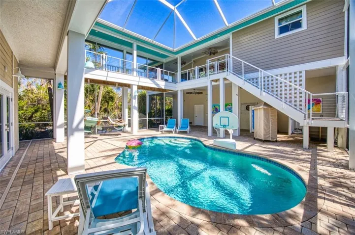 Swimming pool with a patio, a balcony, stairs, a lanai, and a wooden deck