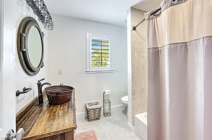 Full bath with vanity, shower / bath combo with shower curtain, and light tile patterned floors
