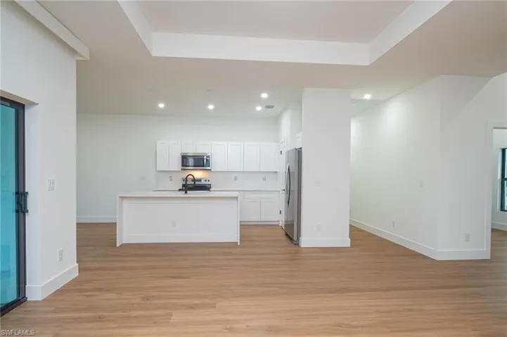 Kitchen featuring sink, an island with sink, appliances with stainless steel finishes, light hardwood / wood-style floors, and white cabinetry