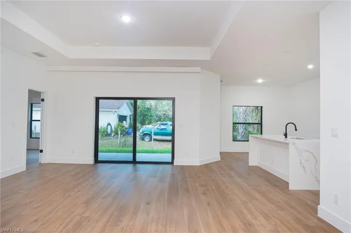 Unfurnished living room featuring light hardwood / wood-style floors, plenty of natural light, and a tray ceiling