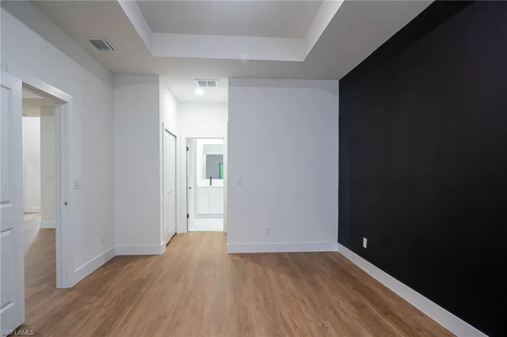 Unfurnished room featuring a tray ceiling and light wood-type flooring