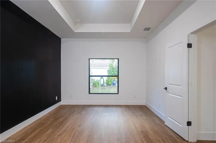 Spare room featuring a tray ceiling and wood-type flooring