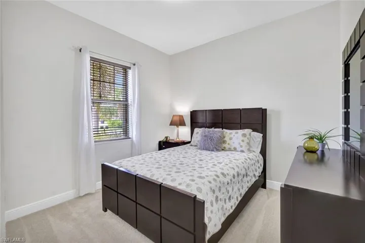Bedroom featuring light carpet and baseboards