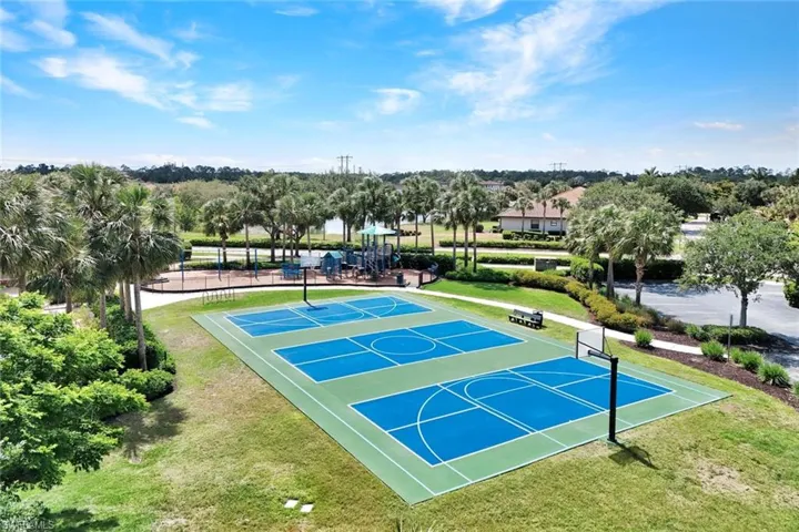 View of basketball court with community basketball court, a lawn, and view of wooded area