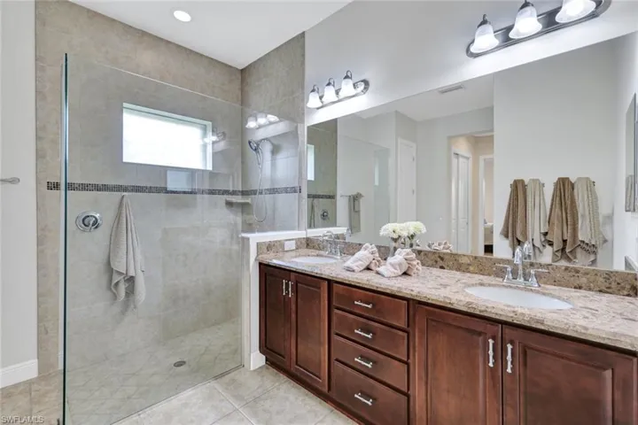 Full bath with walk in shower, double vanity, and tile patterned flooring