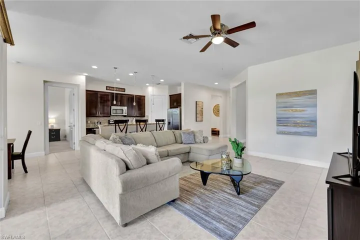 Living room featuring light tile patterned flooring, ceiling fan, baseboards, and recessed lighting