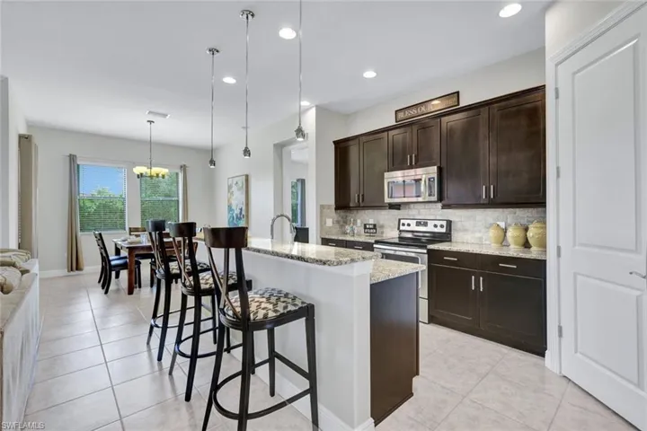 Kitchen featuring appliances with stainless steel finishes, backsplash, a breakfast bar area, a chandelier, and light stone countertops