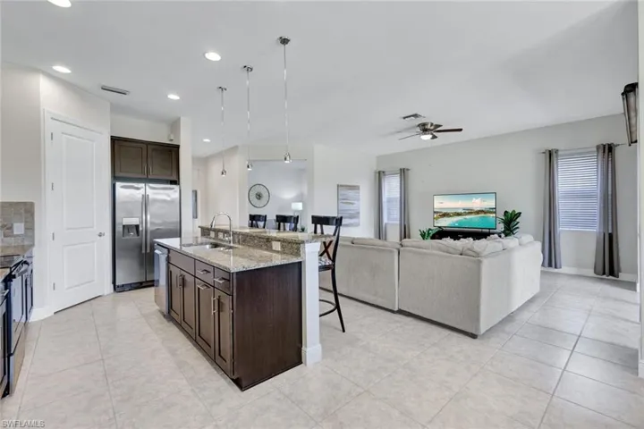 Kitchen featuring a sink, appliances with stainless steel finishes, a kitchen breakfast bar, a ceiling fan, and dark brown cabinetry