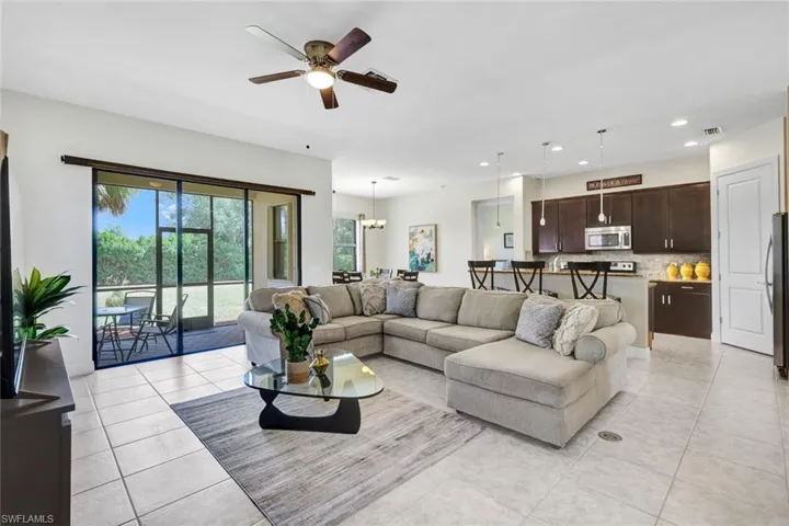 Living room featuring light tile patterned floors, ceiling fan, recessed lighting, and a chandelier