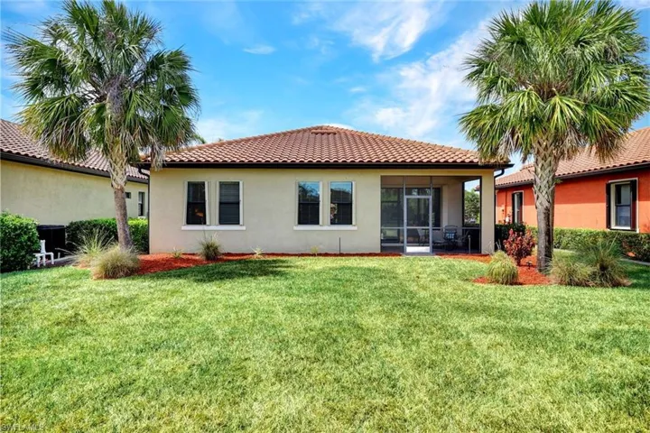 Back of property with stucco siding, a tiled roof, and a yard