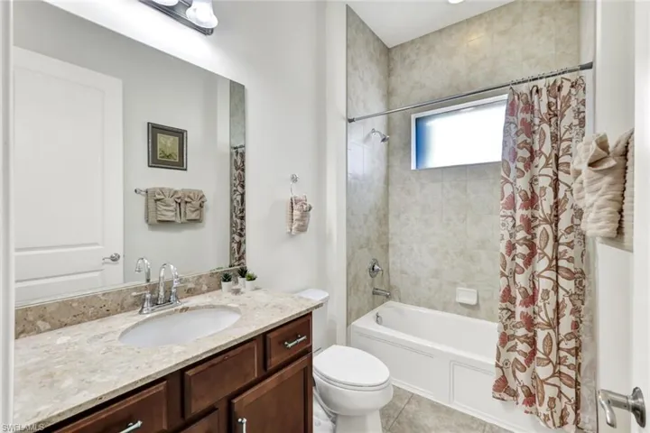Full bathroom featuring toilet, shower / bathtub combination with curtain, vanity, and tile patterned flooring