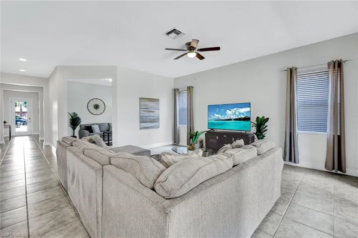 Living area featuring light tile patterned floors, a ceiling fan, baseboards, and recessed lighting
