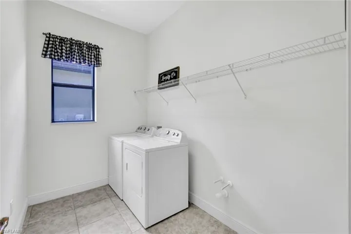 Washroom with washer and dryer, baseboards, and light tile patterned floors