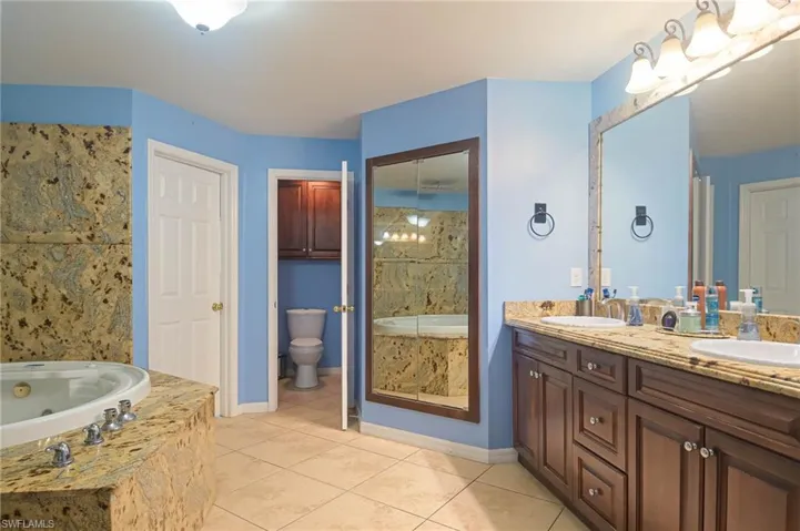 Full bathroom featuring a tub with jets, tile patterned floors, and double vanity