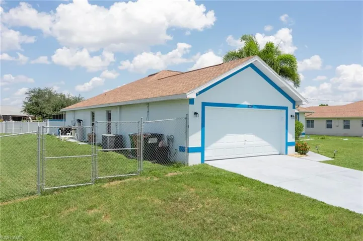 View of home's exterior featuring a gate, stucco siding, concrete driveway, an attached garage, and a shingled roof