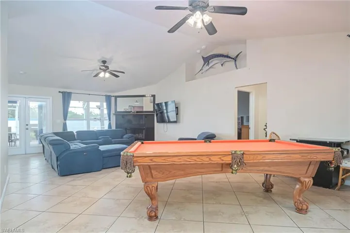Playroom featuring a ceiling fan, billiards table, light tile patterned floors, french doors, and high vaulted ceiling