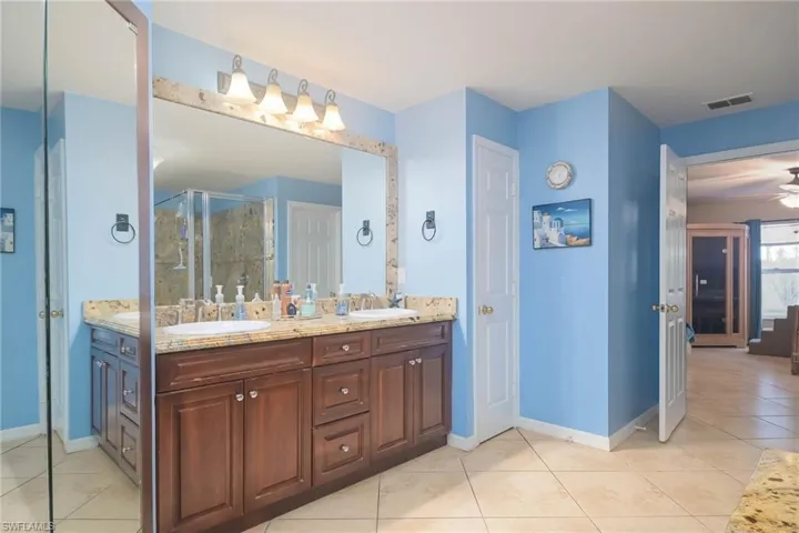 Bathroom with double vanity, tile patterned flooring, a stall shower, ceiling fan, and ensuite bathroom
