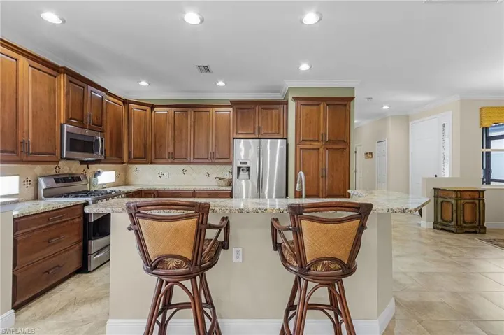 Kitchen featuring light tile patterned floors, light stone counters, and stainless steel appliances