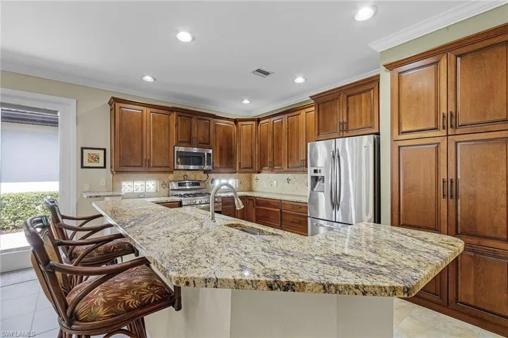 Kitchen featuring decorative backsplash, sink, a breakfast bar area, appliances with stainless steel finishes, and light tile patterned floors