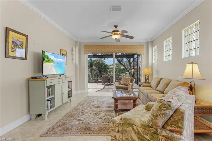 Tiled living room featuring crown molding and ceiling fan