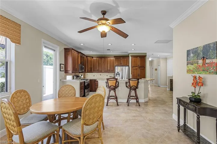 Tiled dining space with ceiling fan and ornamental molding