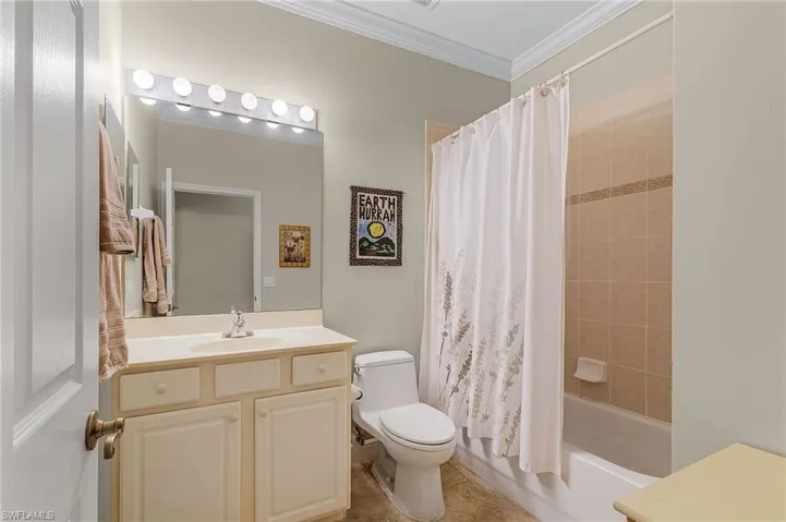 Full bathroom with tile patterned flooring, toilet, vanity, shower / tub combo with curtain, and ornamental molding