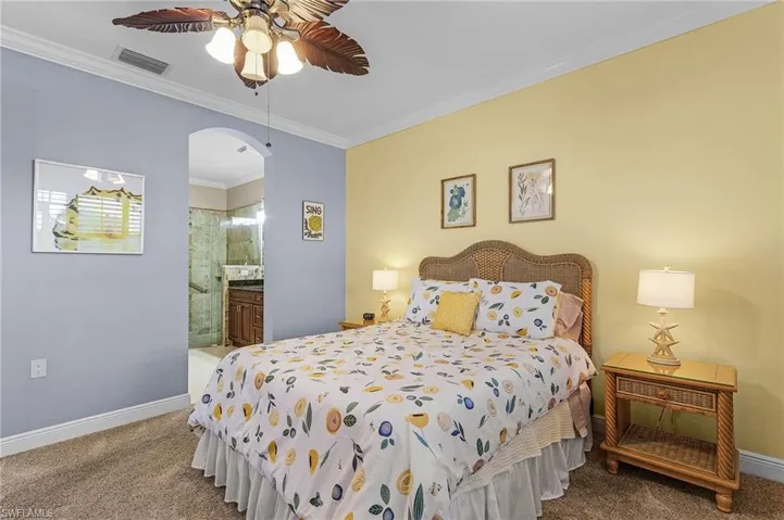 Bedroom featuring ensuite bath, ornamental molding, ceiling fan, and carpet flooring