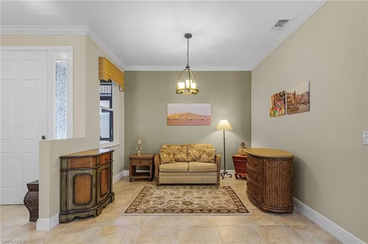 Living area featuring a notable chandelier, light tile patterned flooring, and crown molding