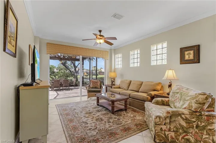 Tiled living room with ornamental molding, a healthy amount of sunlight, and ceiling fan